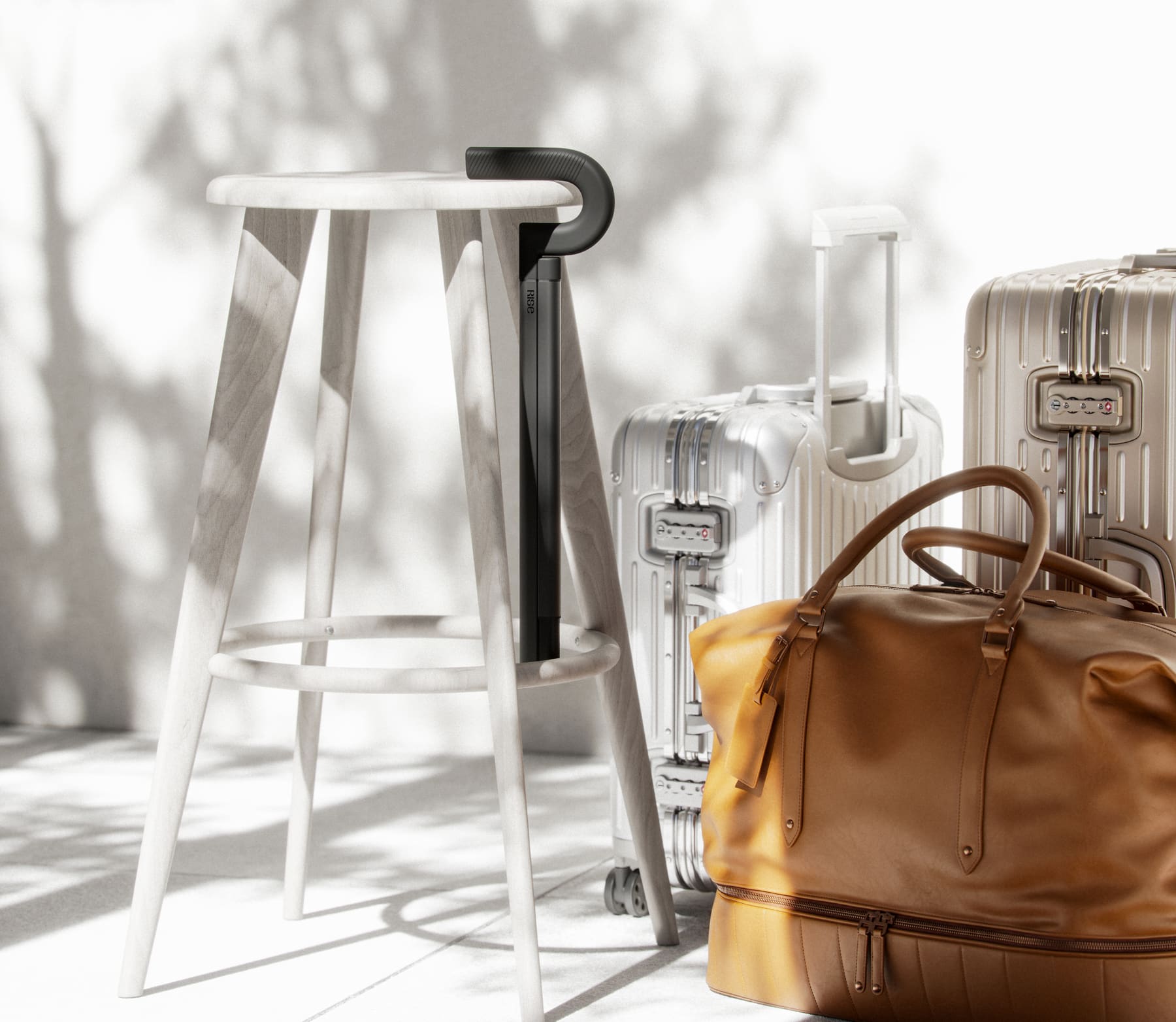 The Rise cane leaning against a wooden stool beside travel luggage